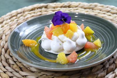 Gâteau de fête décoré de bougies scintillantes, entouré de desserts et de convives en arrière-plan flou.