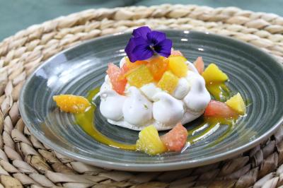 Gâteau de fête décoré de bougies scintillantes, entouré de desserts et de convives en arrière-plan flou.