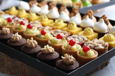 Gâteau de fête décoré de bougies scintillantes, entouré de desserts et de convives en arrière-plan flou.