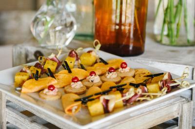 Gâteau de fête décoré de bougies scintillantes, entouré de desserts et de convives en arrière-plan flou.