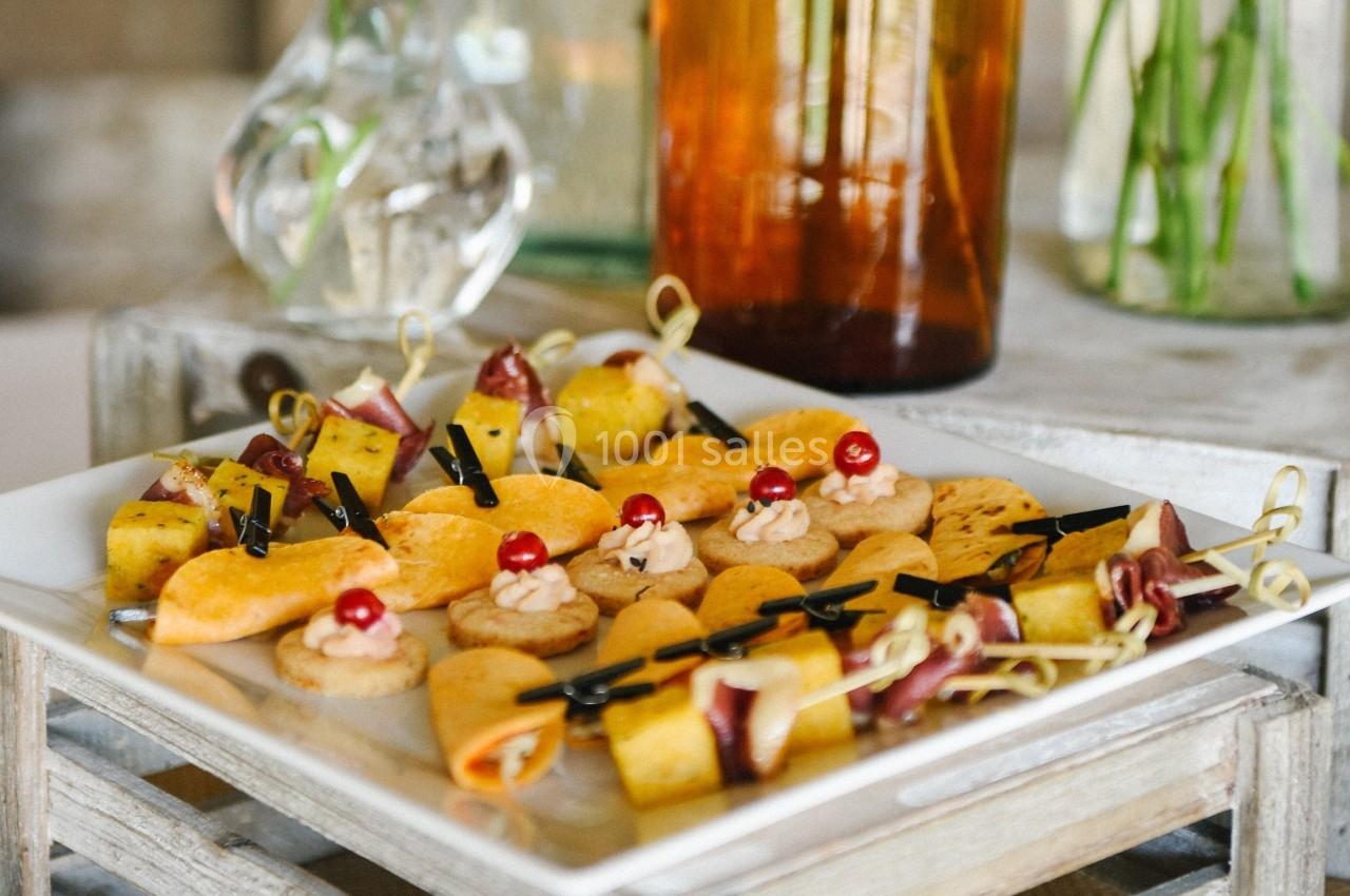 Assortiment de bouchées apéritives sur un plateau, comprenant fruits, fromage et charcuterie, présentées sur des piques.