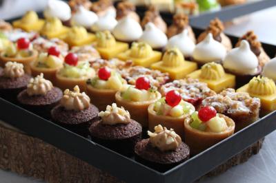 Gâteau de fête décoré de bougies scintillantes, entouré de desserts et de convives en arrière-plan flou.