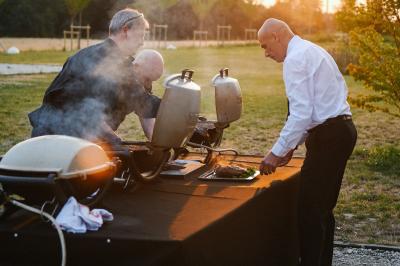 Gâteau de fête décoré de bougies scintillantes, entouré de desserts et de convives en arrière-plan flou.