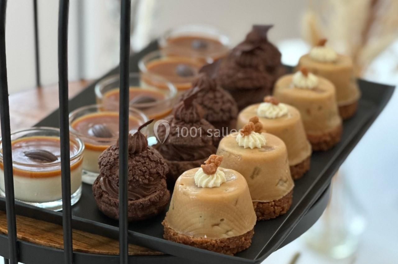 Plateau de desserts variés comprenant choux au chocolat, entremets au caramel et verrines de panna cotta.