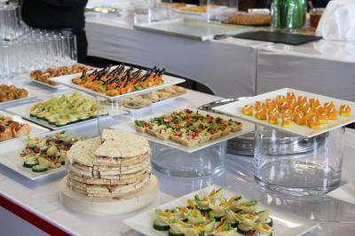 Gâteau de fête décoré de bougies scintillantes, entouré de desserts et de convives en arrière-plan flou.