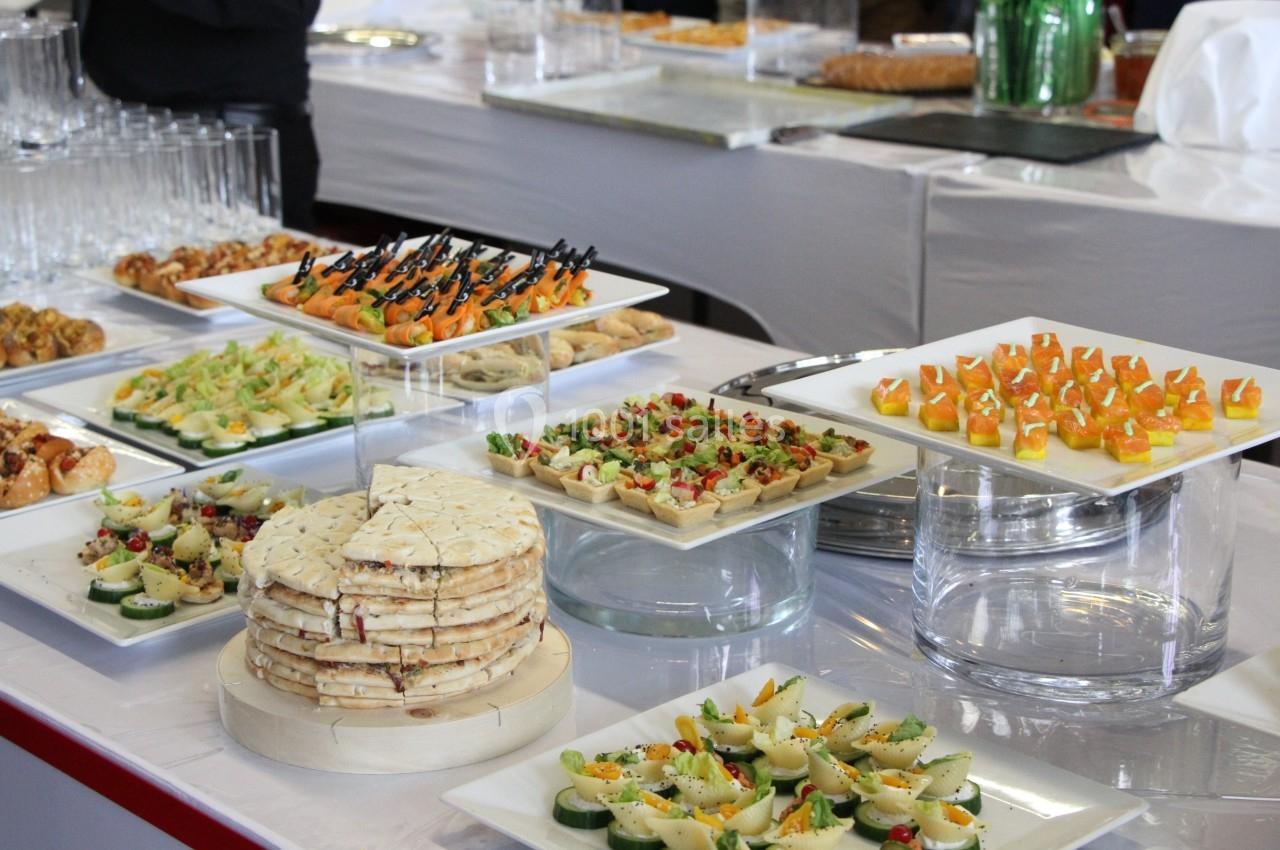 Buffet avec une variété de plats salés, incluant canapés, brochettes et amuse-bouches, disposés sur des plateaux.