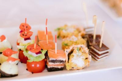 Gâteau de fête décoré de bougies scintillantes, entouré de desserts et de convives en arrière-plan flou.