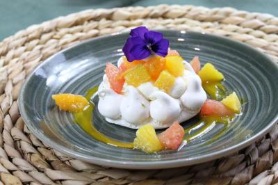 Gâteau de fête décoré de bougies scintillantes, entouré de desserts et de convives en arrière-plan flou.