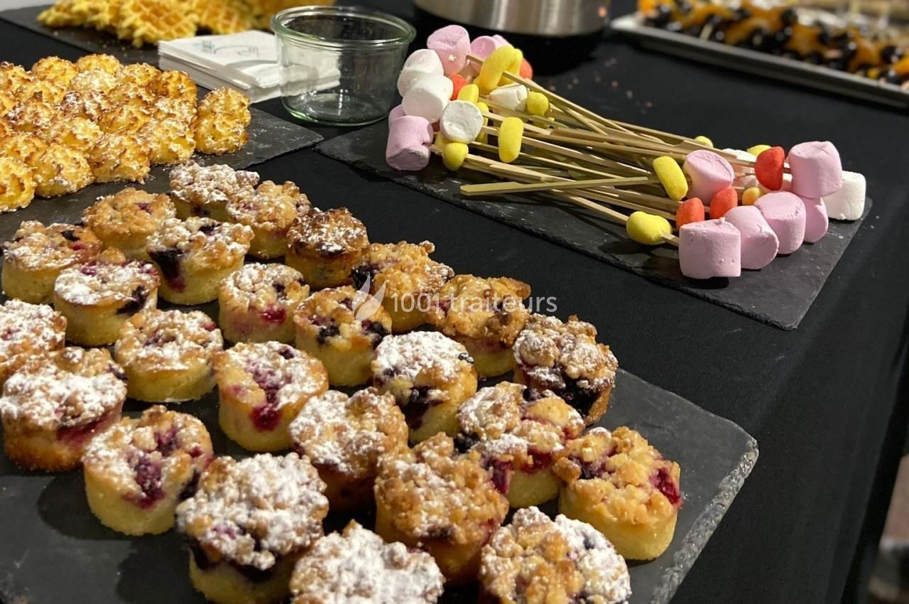 Plateau de desserts variés comprenant des muffins aux fruits, des brochettes de guimauves et des pâtisseries.