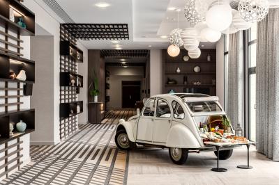 Salle de sport lumineuse avec tapis de course, vélos, haltères et coin détente avec fauteuils en osier.
