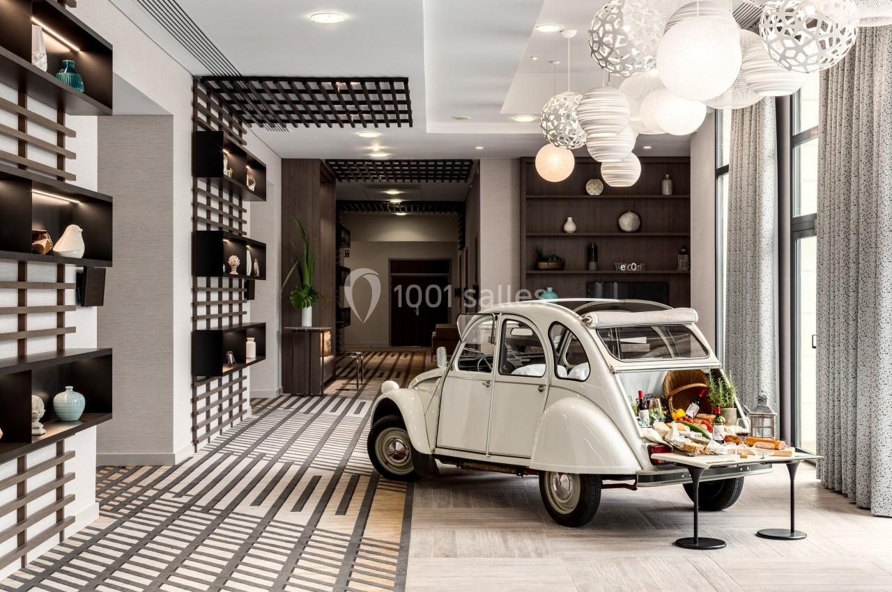 Une voiture ancienne blanche exposée dans un intérieur moderne, utilisée comme support pour un buffet décoratif.