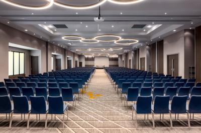 Salle de sport lumineuse avec tapis de course, vélos, haltères et coin détente avec fauteuils en osier.