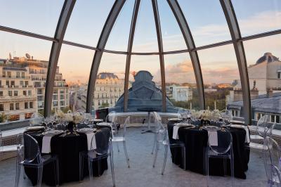 Vue d'une terrasse urbaine et d'un espace intérieur vitré avec parquet, offrant une perspective sur des bâtiments parisiens.