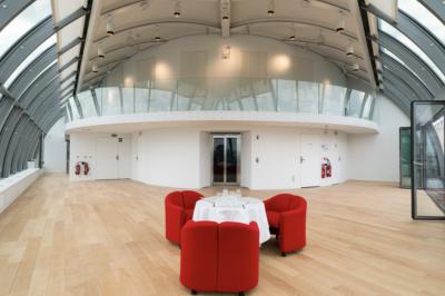 Vue d'une terrasse urbaine et d'un espace intérieur vitré avec parquet, offrant une perspective sur des bâtiments parisiens.