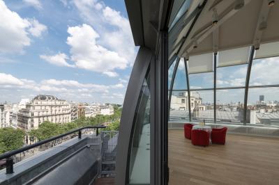 Vue d'une terrasse urbaine et d'un espace intérieur vitré avec parquet, offrant une perspective sur des bâtiments parisiens.