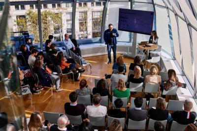 Vue d'une terrasse urbaine et d'un espace intérieur vitré avec parquet, offrant une perspective sur des bâtiments parisiens.