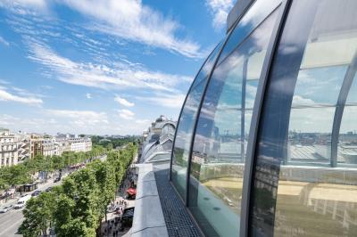 Vue d'une terrasse urbaine et d'un espace intérieur vitré avec parquet, offrant une perspective sur des bâtiments parisiens.