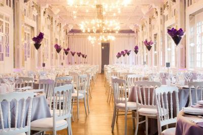 Salle lumineuse avec parquet en bois, murs blancs, mobilier noir et grandes fenêtres laissant entrer la lumière naturelle.