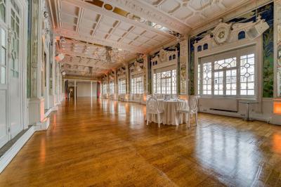 Salle lumineuse avec parquet en bois, murs blancs, mobilier noir et grandes fenêtres laissant entrer la lumière naturelle.