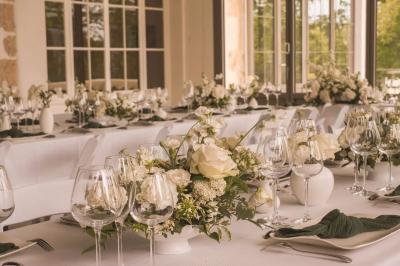 Façade d'une maison ancienne avec volets bleus, entourée de végétation et éclairée par des guirlandes lumineuses.