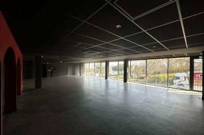 Cour intérieure avec sol en bois, quatre tonneaux et deux grandes sphères blanches près d'un mur et d'une porte vitrée.