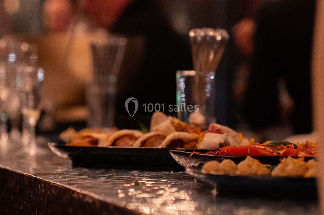 Assiettes de plats variés disposées sur un comptoir dans une ambiance tamisée.