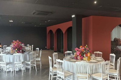 Cour intérieure avec sol en bois, quatre tonneaux et deux grandes sphères blanches près d'un mur et d'une porte vitrée.
