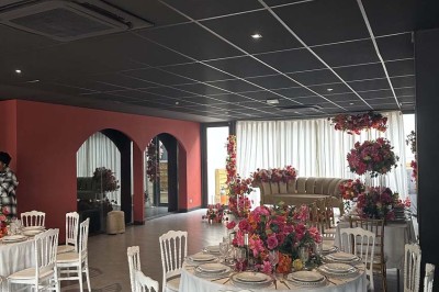 Cour intérieure avec sol en bois, quatre tonneaux et deux grandes sphères blanches près d'un mur et d'une porte vitrée.