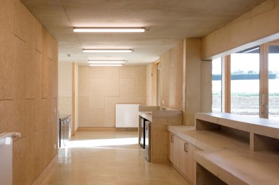 Cuisine professionnelle avec plans de travail en inox sur roulettes, four industriel et carrelage au sol.