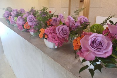 Miniature Location salle Chablis (Yonne) - Le Kimmeridgien #25 Bouquets de roses violettes, hortensias roses et petites fleurs orange alignés sur un comptoir en béton.