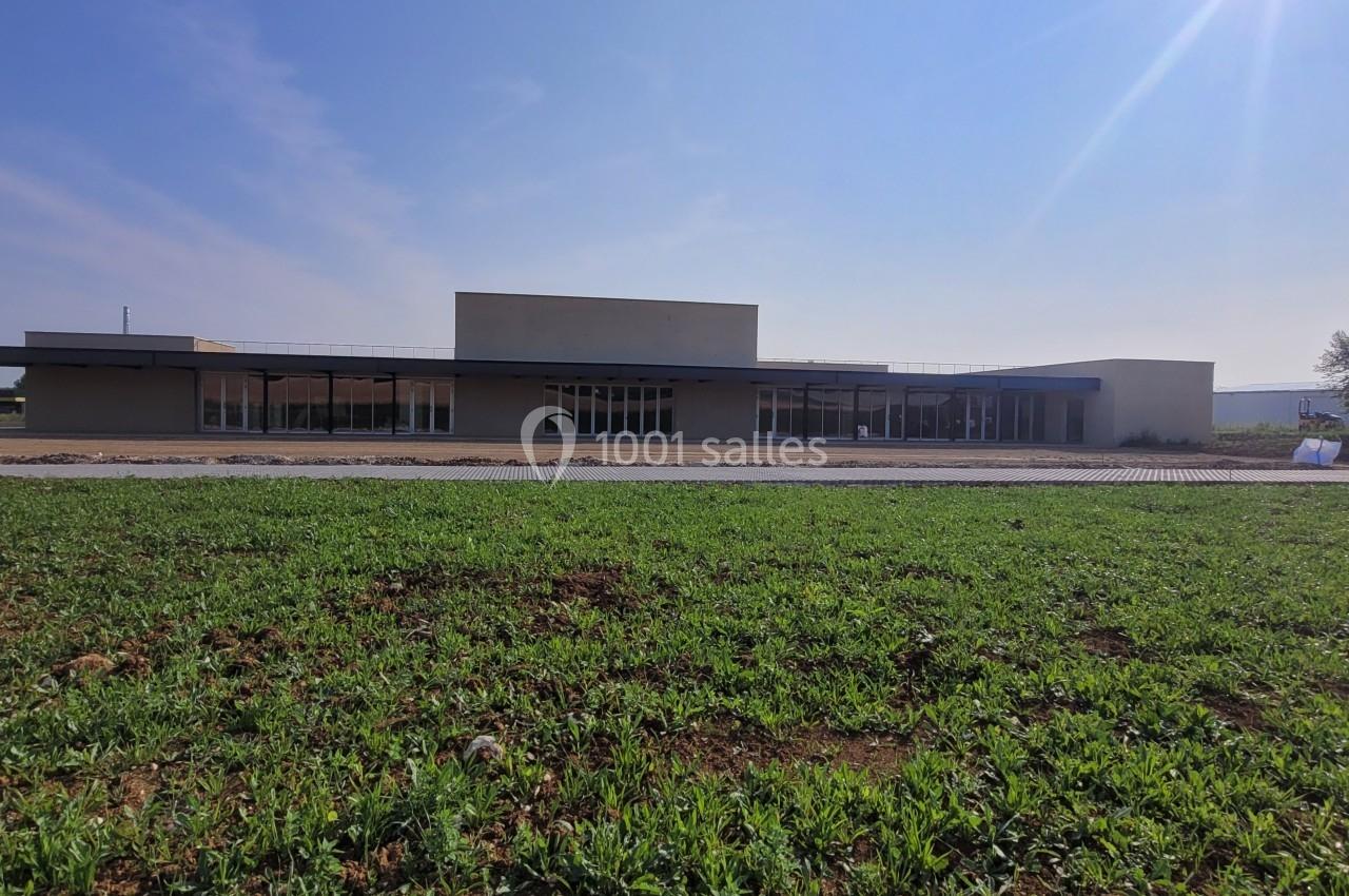 Bâtiment moderne de plain-pied entouré d'une étendue d'herbe sous un ciel dégagé.