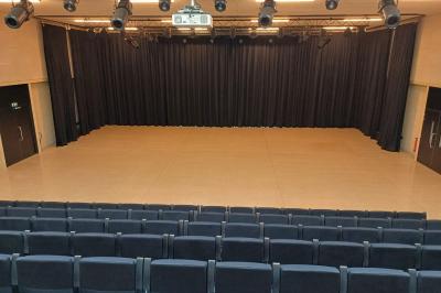Paysage rural avec des champs cultivés, une maison isolée et une forêt en arrière-plan sous un ciel bleu.