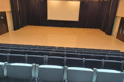 Paysage rural avec des champs cultivés, une maison isolée et une forêt en arrière-plan sous un ciel bleu.