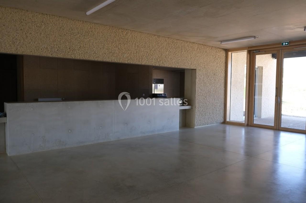 Intérieur d'un bâtiment avec un comptoir en béton, un sol en béton poli et de grandes fenêtres laissant entrer la lumière.