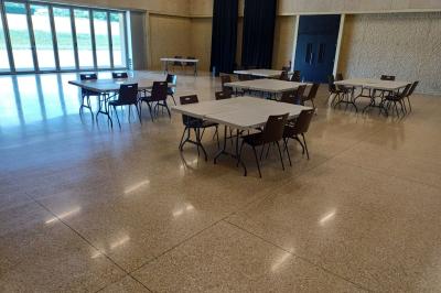 Paysage rural avec des champs cultivés, une maison isolée et une forêt en arrière-plan sous un ciel bleu.