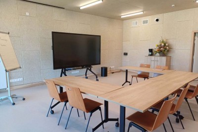 Paysage rural avec des champs cultivés, une maison isolée et une forêt en arrière-plan sous un ciel bleu.