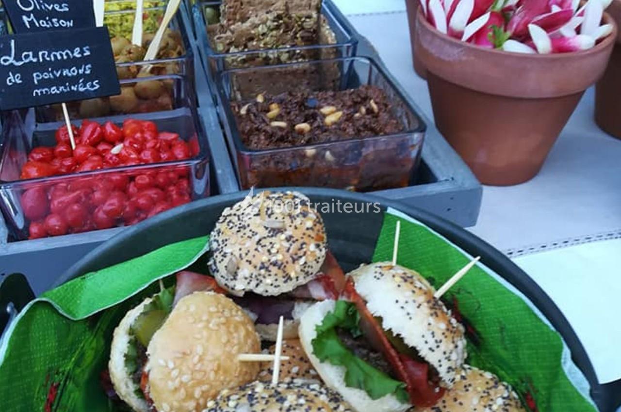 Plateau de mini-burgers garnis devant des bols de condiments variés, légumes marinés et tartinades.