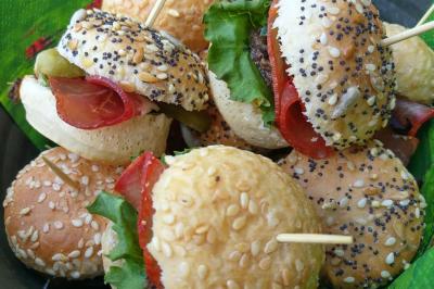 Bagels au sésame garnis de fromage frais, de légumes verts et d'herbes, disposés sur un plateau.