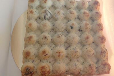 Bagels au sésame garnis de fromage frais, de légumes verts et d'herbes, disposés sur un plateau.