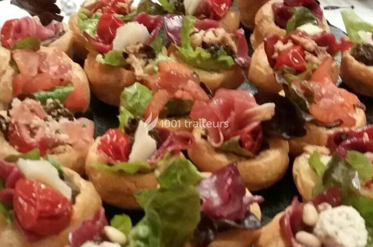 Assortiment de bouchées garnies de légumes, charcuterie, fromage et salade sur un plateau.