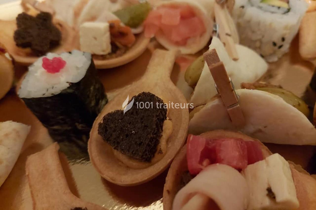 Assortiment de bouchées apéritives variées, incluant sushis, toasts et mini-brochettes, présenté sur un plateau.