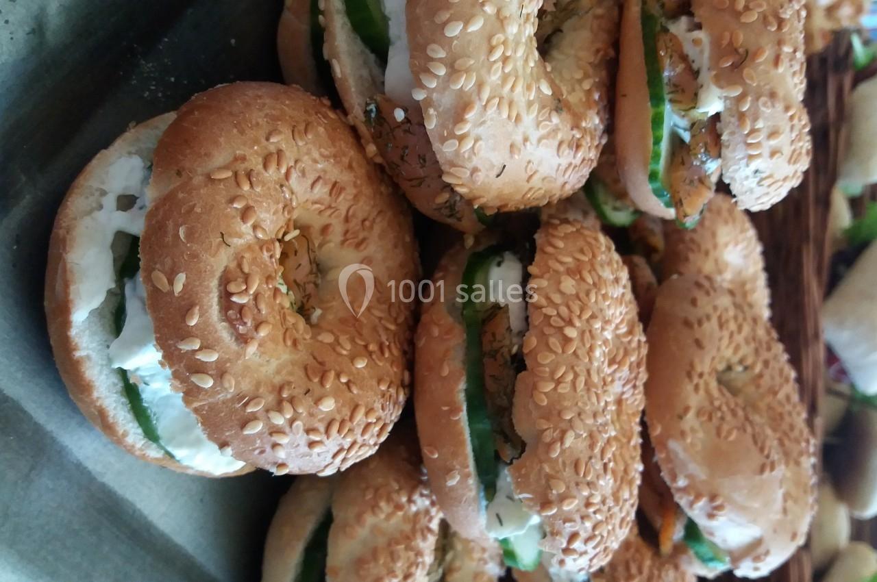 Bagels au sésame garnis de fromage frais, de légumes verts et d'herbes, disposés sur un plateau.