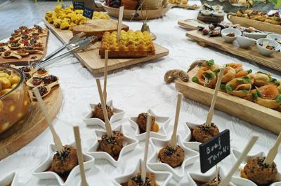 Buffet varié avec amuse-bouches, verrines, tartes salées et plats colorés disposés sur une nappe blanche.