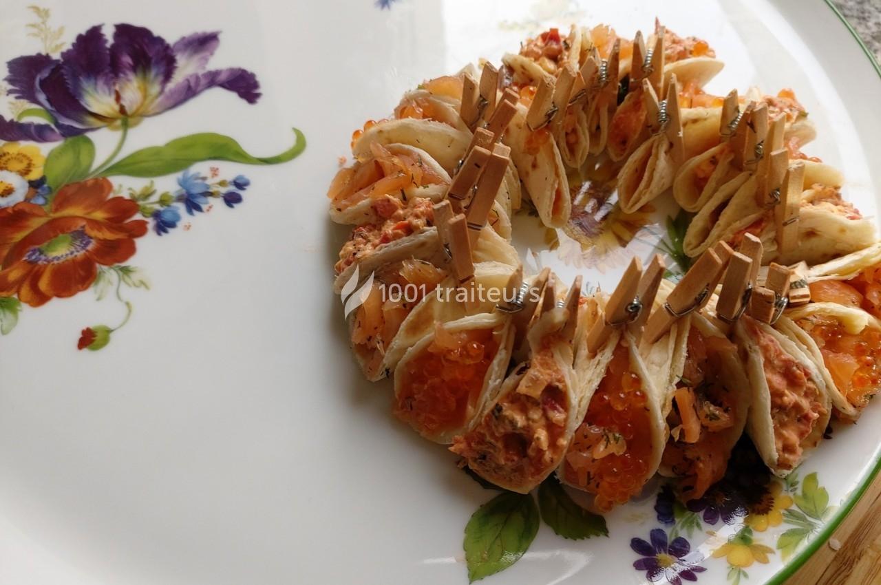 Assiette décorée contenant une présentation circulaire de bouchées garnies de saumon et maintenues par des pinces en bois.