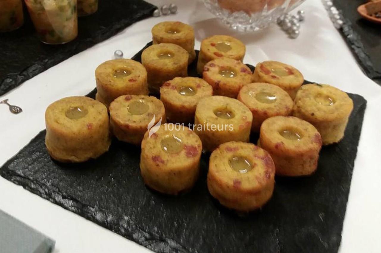 Assortiment de bouchées apéritives disposées sur une ardoise noire, garnies d'une sauce au centre.