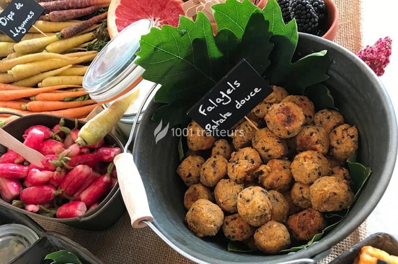 Boules de falafels à la patate douce dans un bol en métal, entourées de légumes frais et de fruits.