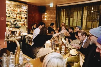 Table sombre avec des verres à vin, une assiette de nourriture et un seau à champagne, éclairée par des bougies.