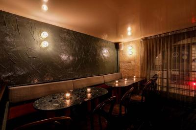 Table sombre avec des verres à vin, une assiette de nourriture et un seau à champagne, éclairée par des bougies.