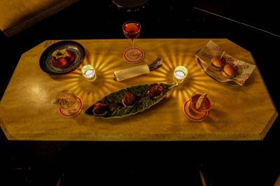 Table sombre avec des verres à vin, une assiette de nourriture et un seau à champagne, éclairée par des bougies.