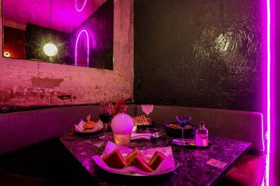 Table sombre avec des verres à vin, une assiette de nourriture et un seau à champagne, éclairée par des bougies.